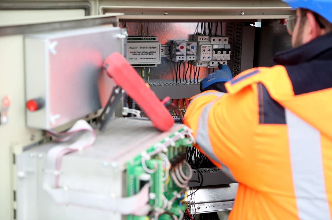 Technician working on control and automation hardware in a panel